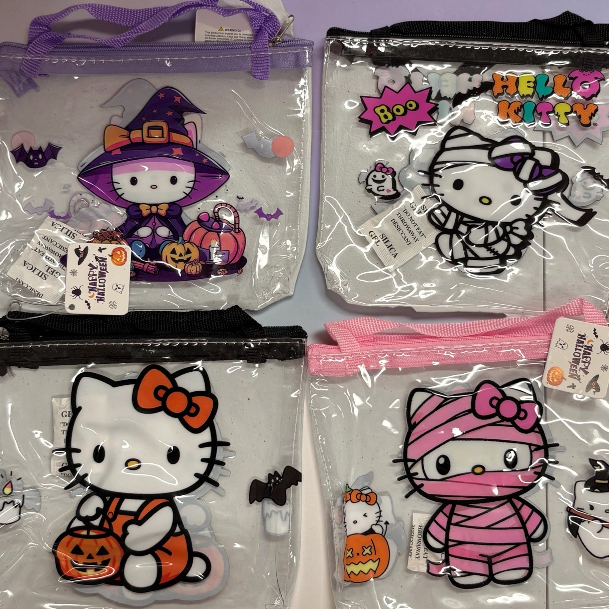 Four clear zippered Hello Kitty Halloween-themed pouches. The pouches feature different character designs in costumes: a purple witch outfit, a black-and-white ghost costume, an orange pumpkin/witch outfit, and a pink mummy costume.